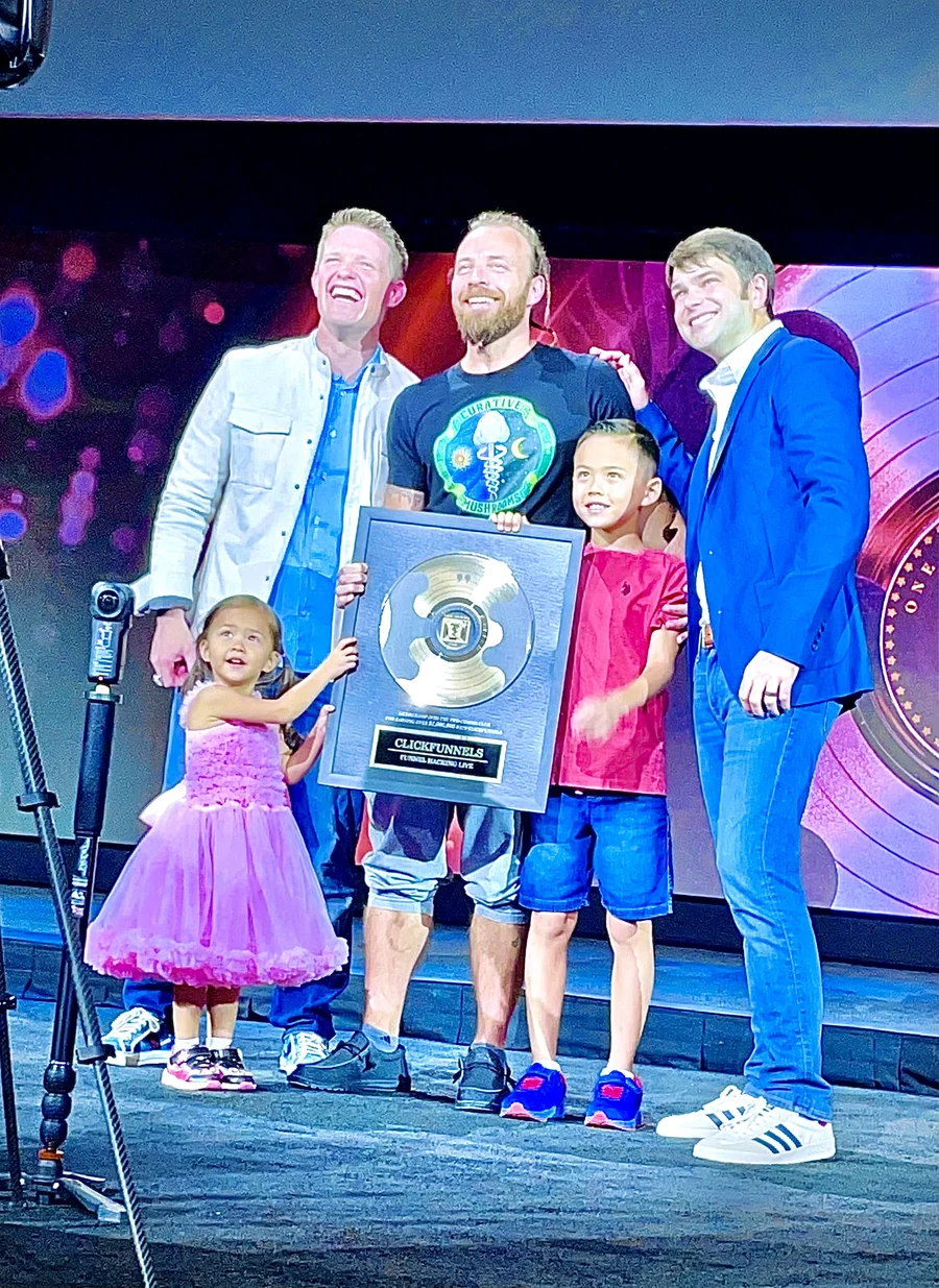Oliver and his family with Russell Brunson at the ClickFunnels Two Comma Club award presentation